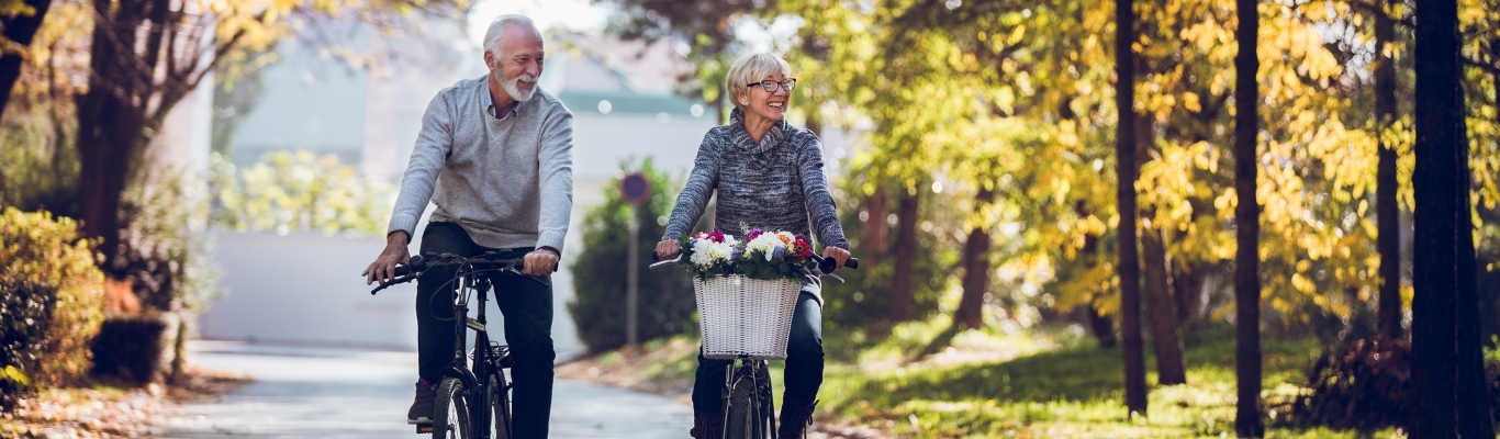 Older couple riding bikes in park