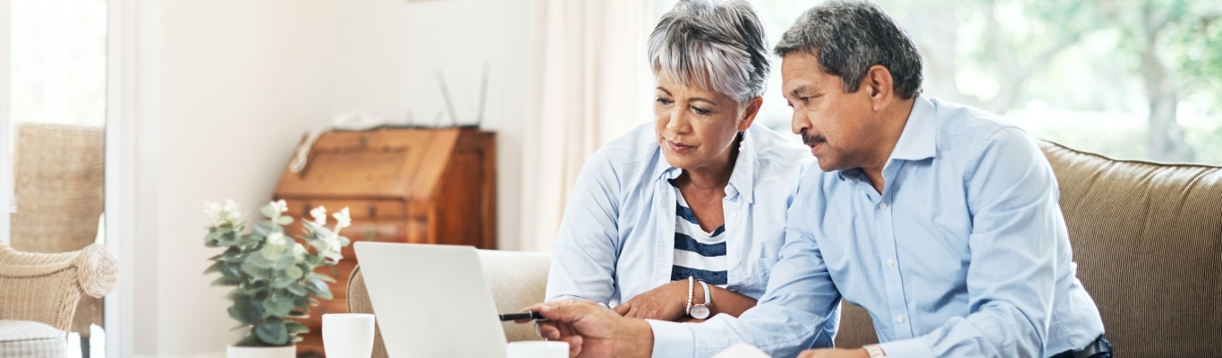 Senior Couple Discussing Something on Couch with Laptop in Front of Them