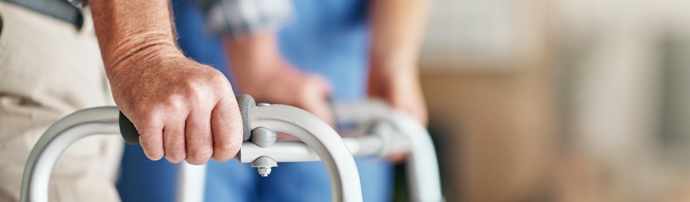 Male hands on walker with nurse in background