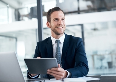 Happy business man with tablet at desk